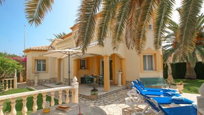 A hotel with a patio area featuring lounge chairs, a table with a drink, and a decorative fountain. - Villa with pool in Denia La Giralda BO (Denia)