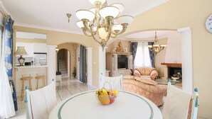 A dining area with a round table, chairs, a chandelier, and a fruit basket. - Villa with pool in Denia La Giralda BO (Denia)