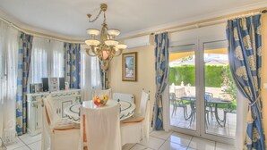 A dining area with a round table, chairs, a chandelier, and curtains. - Villa with pool in Denia La Giralda BO (Denia)
