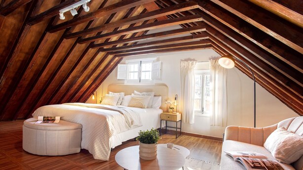 A cozy attic bedroom with a bed, a sofa, a round coffee table, and a small side table. - Genteel Home Trinidad Grund C (Málaga)