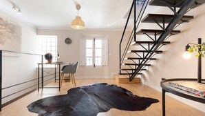 A modern interior with a staircase, a dining area, and a large black leather rug. - Genteel Home Trinidad Grund C (Málaga)