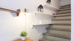 A staircase with wooden steps, white walls, and a wooden table with a potted plant. - Uffizi apartment Spacious and comfortable apartment (Firenze)