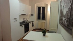 A compact kitchen with white cabinets, a dining table, and chairs. - Uffizi apartment Spacious and comfortable apartment (Firenze)