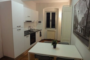 Cocina pequeña con armarios blancos, una mesa de comedor y sillas.