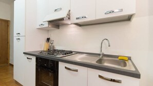 A modern kitchen with white cabinets, a gas stove, a stainless steel sink, and a black oven. - Uffizi apartment Spacious and comfortable apartment (Firenze)