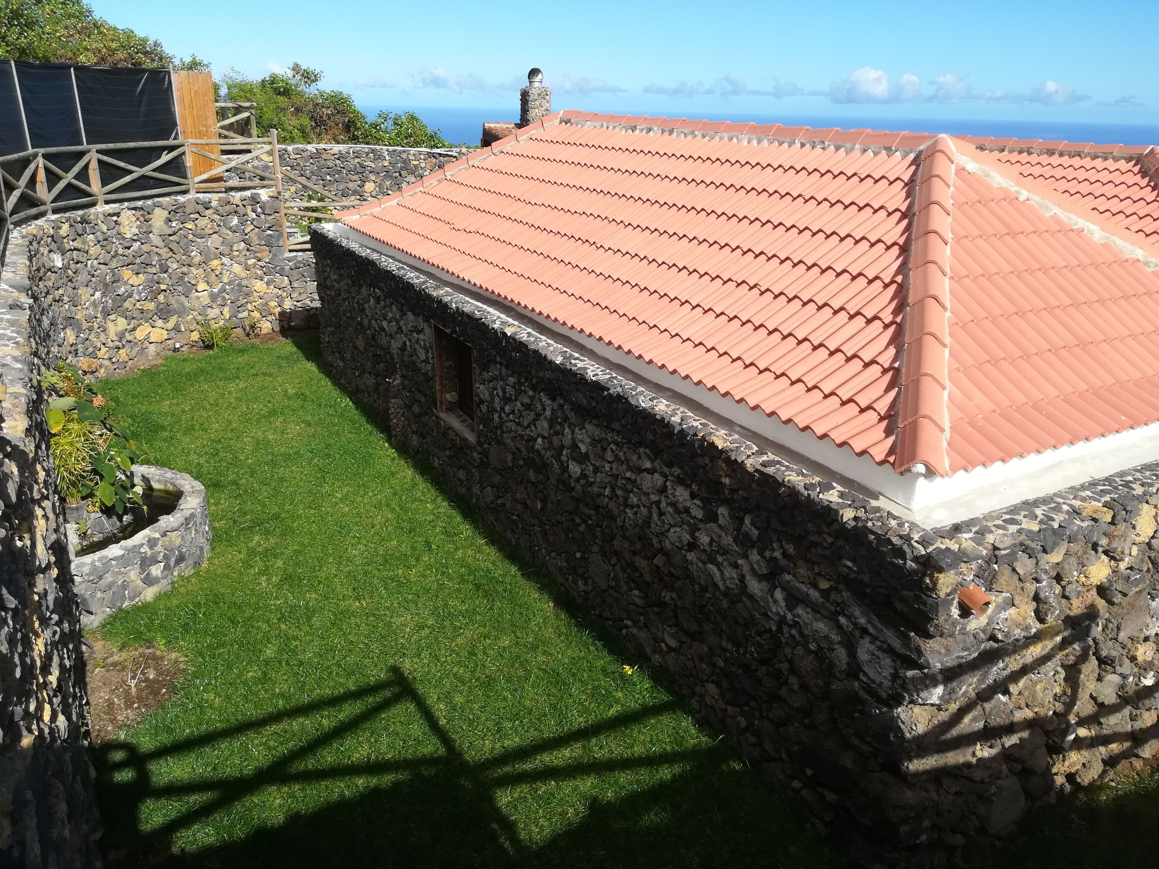 Un bâtiment en pierre avec un toit recouvert de tuiles rouges et une petite fenêtre.