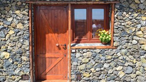 A rustic stone wall with a wooden door and a window with a flower box.