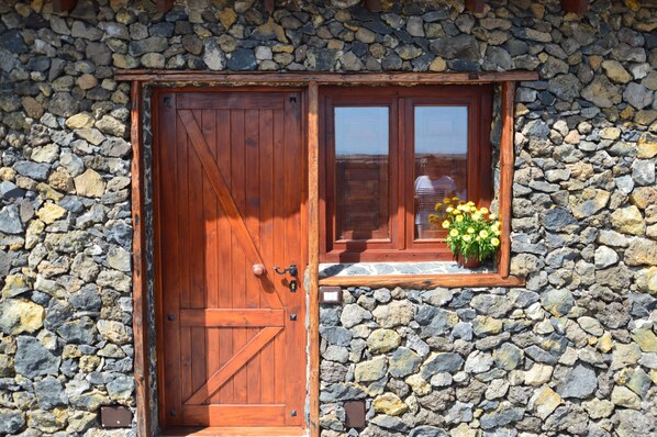 A rustic stone wall with a wooden door and a window with a flower box.