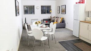 A modern, compact living space with a dining area, sofa, and kitchen.