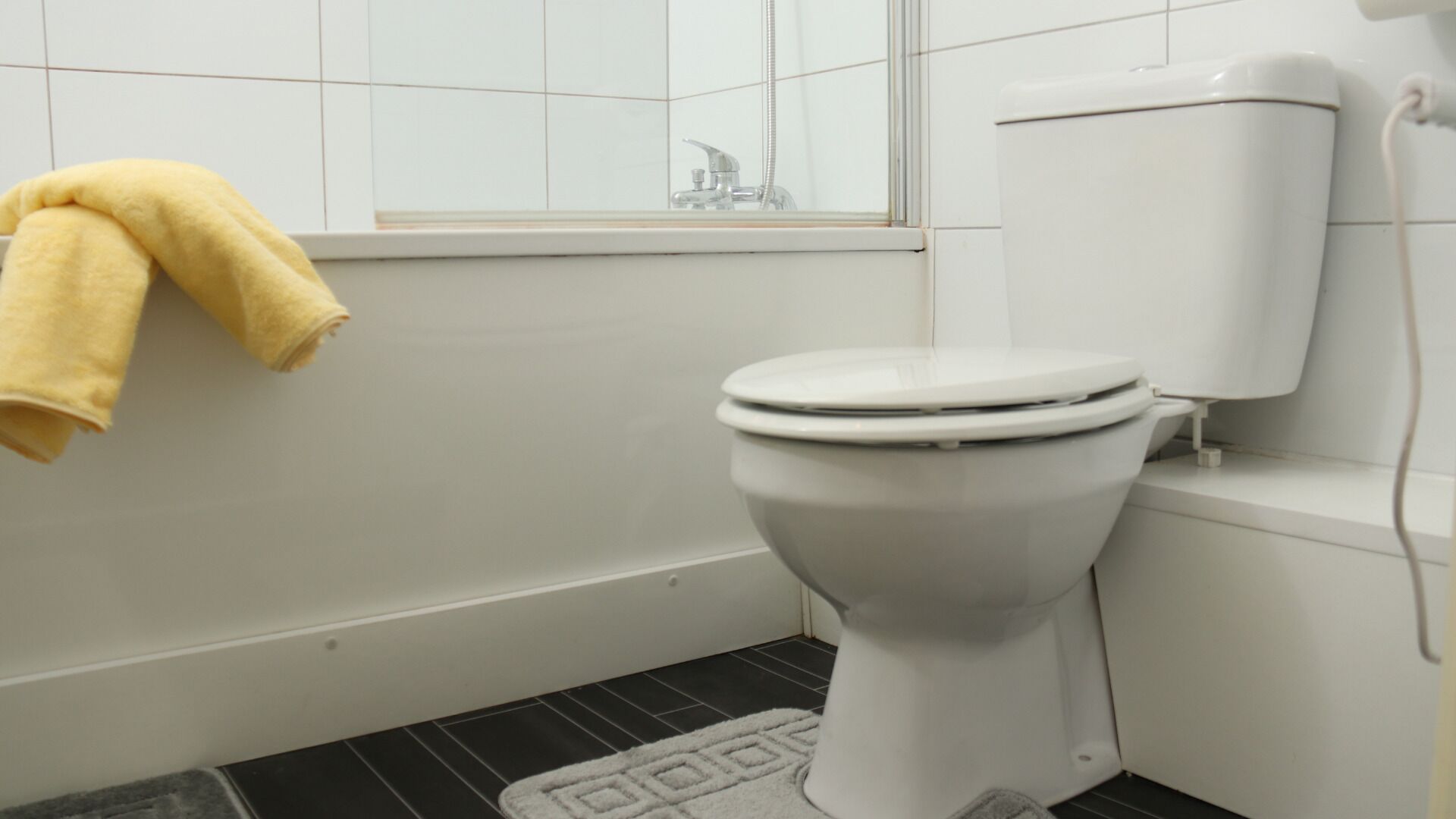 A bathroom with a toilet, a bathtub, and a window.
