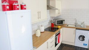 A compact kitchen with a refrigerator, microwave, sink, and washing machine.