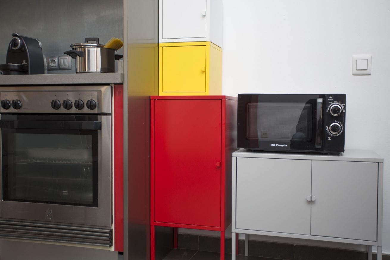 Une cuisine équipée d’un four en acier inoxydable, d’un four à micro-ondes et d’un meuble rouge.