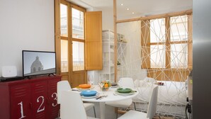 Een eethoek met een ronde tafel, witte stoelen en een rode opbergkast met cijfers.
