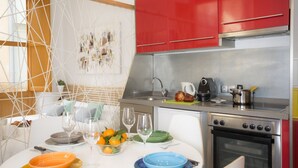 Een moderne keuken met rode kastjes, roestvrijstalen apparatuur en een eethoek met een witte tafel, gedekt met borden en glazen.