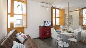 Een moderne woonkamer met een bruine leren bank, een rode kast en een eethoek met witte stoelen en een tafel.