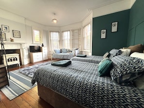 A bedroom with two beds, a fireplace, and a television. - Silverdale Starlight spacious 2 bedroom apt, garden, parking & close to seafront (Eastbourne)