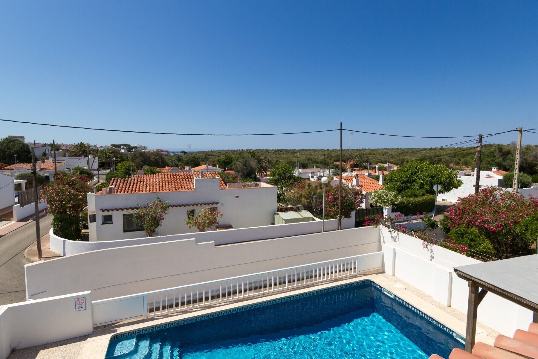 Zona residencial con piscina, edificios blancos y cielo azul despejado.