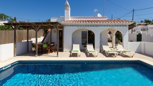 Un área junto a la piscina con una pérgola, asientos al aire libre y sillones reclinables.