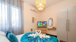 A hotel room with a bed, a television, a wardrobe, and a decorative arrangement on the bed. - Desenzanoloft A Casa di Sara  (Desenzano del Garda)