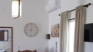 Una sala de estar con un sillón marrón, un reloj de pared redondo, un televisor de pantalla plana y una chimenea.