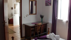 A bedroom with a bed, a desk, a chair, a window with curtains, and a door leading to another room. - Casa Magaída, AC, with terrace, near the Ria (Luz (Luz de Tavira))