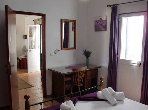 A bedroom with a bed, a desk, a chair, a window with curtains, and a door leading to another room. - Casa Magaída, AC, with terrace, near the Ria (Luz (Luz de Tavira))