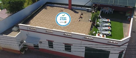 Un bâtiment doté d’une terrasse sur le toit, d’une enseigne indiquant « Propre et sûr », et de places assises à l’extérieur.