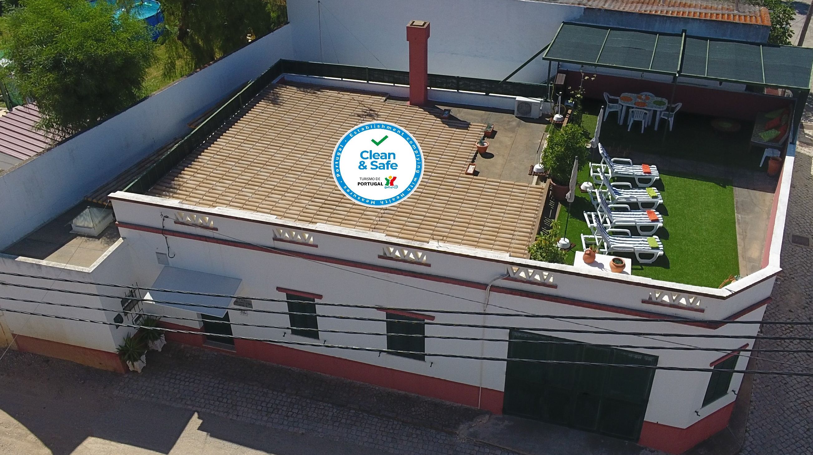 Un edificio con terraza en la azotea, un letrero que indica 'Clean & Safe' y mobiliario exterior.