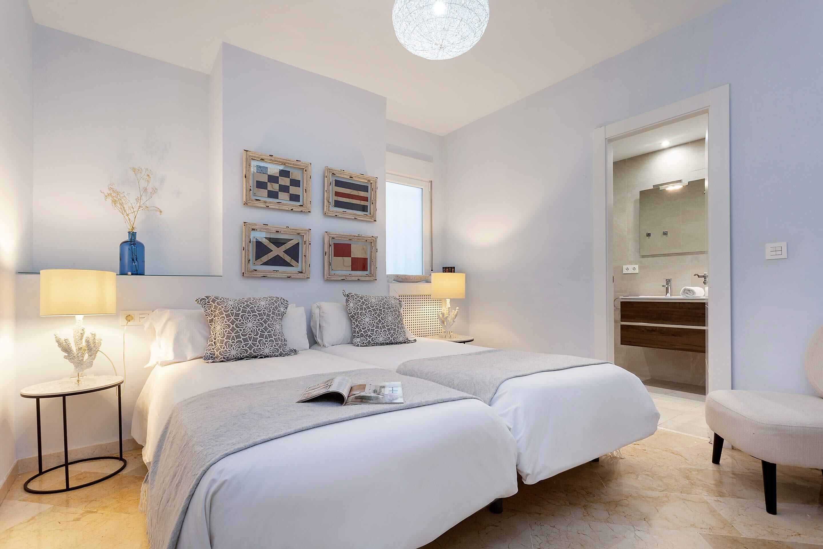 Un dormitorio moderno con dos camas, una mesita de noche, una lámpara y un espejo.