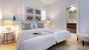 Un dormitorio moderno con dos camas, una mesita de noche, una lámpara y un espejo.