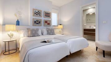 Un dormitorio moderno con dos camas, una mesita de noche, una lámpara y un espejo.