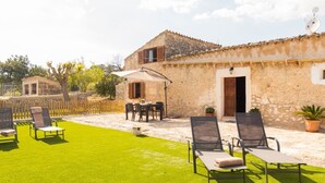 A stone building with a patio area, outdoor seating, and a well-maintained lawn.