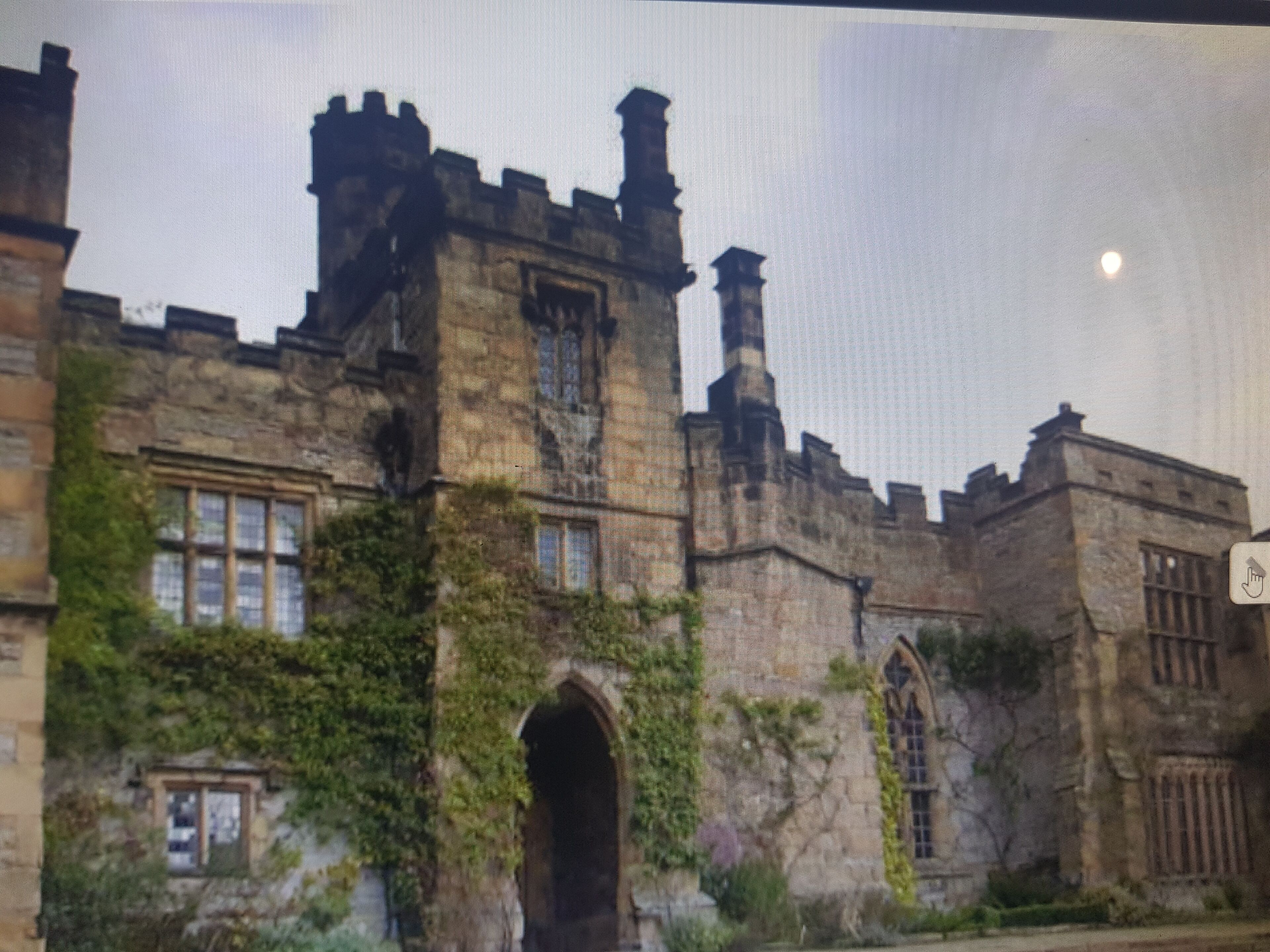 A historic building with stone walls, arched windows, and ivy growth.