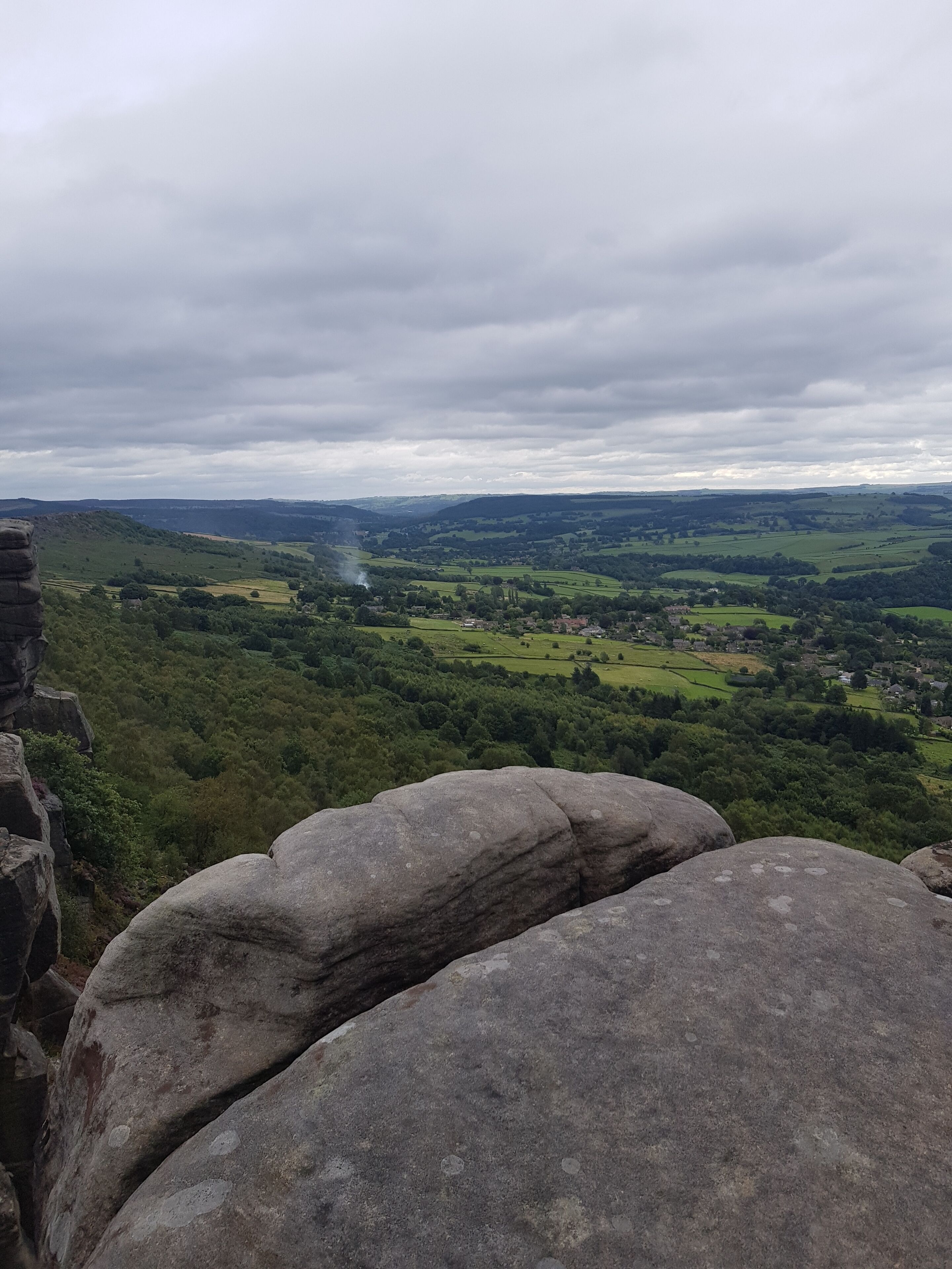 A panoramic view of a valley with a stone structure in the foreground.