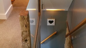 Una escalera con barandilla de madera, una mesita con espejo y una decoración en forma de corazón en la pared.