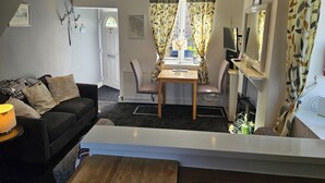 Una sala de estar con sofá, mesa de comedor, televisor y chimenea.