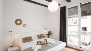 A neatly arranged bedroom with a bed, bedside table, and a view of the outside balcony. - Singular Stays Botanico 201 (València)