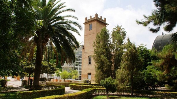 A courtyard with a tower, palm trees, and a glass building. - Singular Stays Botanico 201 (València)