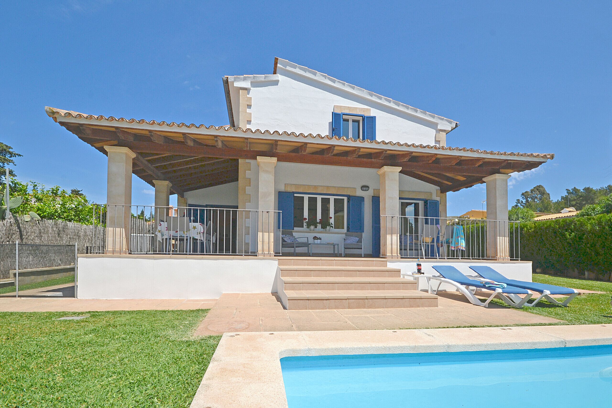 A two-story house with a covered patio, a swimming pool, and a lawn.
