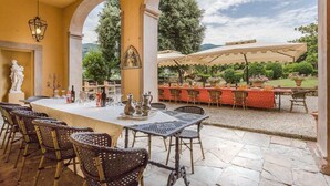An outdoor dining area with a table set for six, surrounded by wicker chairs, under a covered patio. - Villa Controni     . (Capannori)