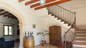 A spacious living area with a wooden staircase, a large barrel, and a potted plant. - Can Toni - Mallorcan style country house in Binissalem (Lloseta)