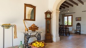 A dining area with a table set for two, a large mirror, a tall grandfather clock, and a bowl of lemons on a table. - Can Toni - Mallorcan style country house in Binissalem (Lloseta)
