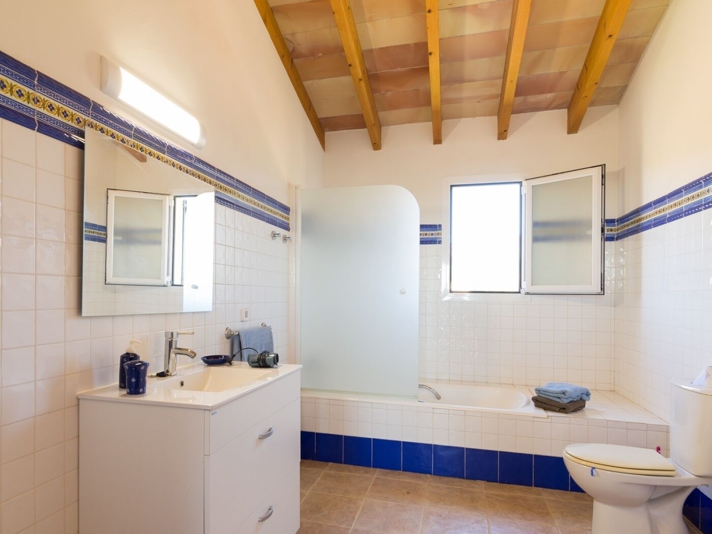 Un baño con lavamanos blanco, espejo, bañera y retrete.