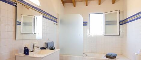 Un baño con lavamanos blanco, espejo, bañera y retrete.