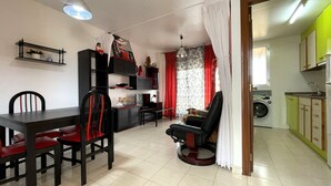 A living room with a dining table, chairs, a sofa, and a washing machine in the background. - Siroco Holidays 5-B LEK (Peñiscola)