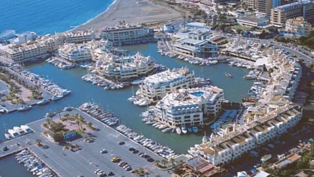 An aerial view of a marina with multiple cruise ships docked, surrounded by buildings and a road with vehicles. - Apartment in Torremolinos (La Carihuela area) Erisa 1. (Torremolinos)