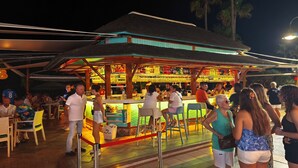 A bar area with a thatched roof, outdoor seating, and a variety of bottles and glasses on display. - Apartment in Torremolinos (La Carihuela area) Erisa 1. (Torremolinos)