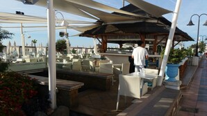 A rooftop bar with outdoor seating, a pool, and a bar area with a bartender. - Apartment in Torremolinos (La Carihuela area) Erisa 1. (Torremolinos)