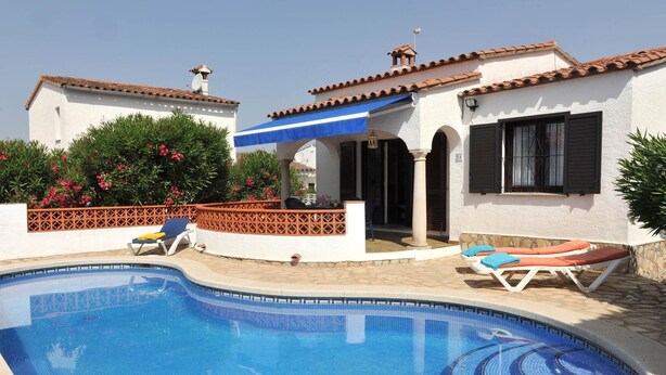 Una piscina con sillas de descanso y un área de patio techada.