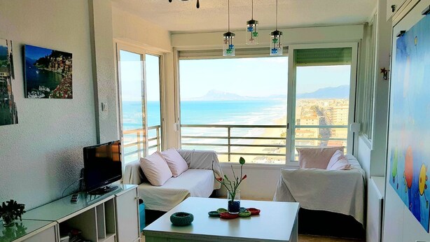 Una habitación con sofá, una mesa con un jarrón y un televisor sobre un mueble.